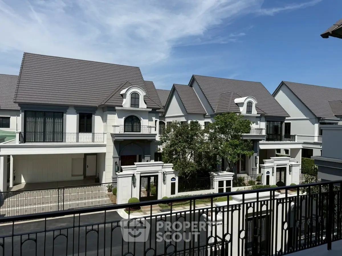 Elegant residential neighborhood with modern houses and lush greenery under a clear blue sky.