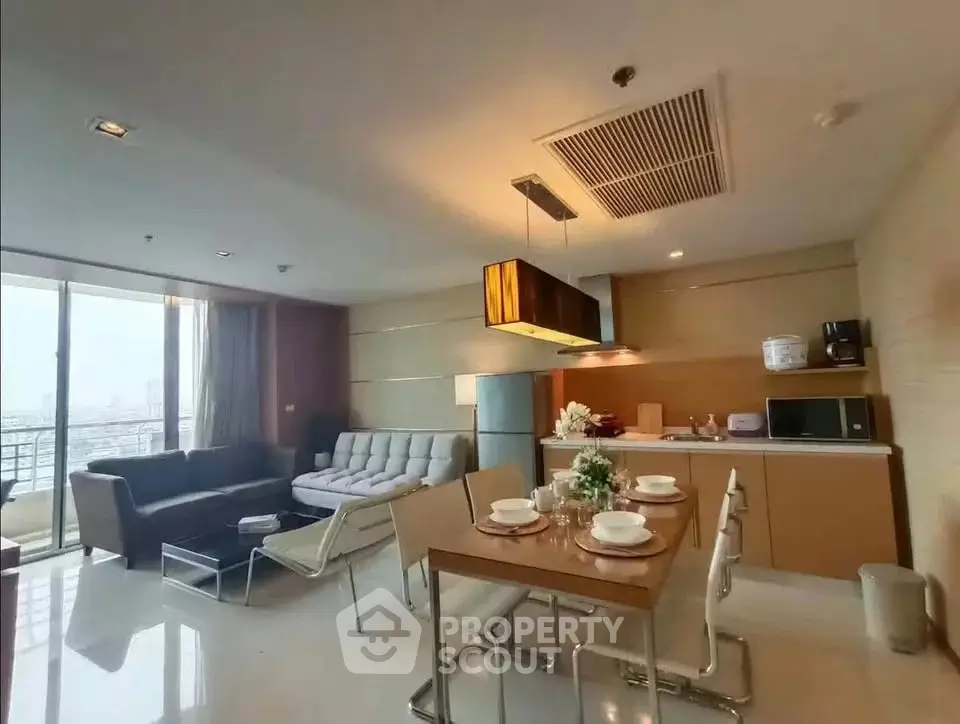Spacious modern living room with open kitchen and dining area, featuring elegant furniture and large windows.
