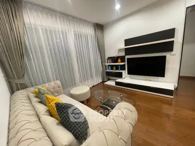 Modern living room with stylish sofa, glass coffee table, and sleek entertainment unit.