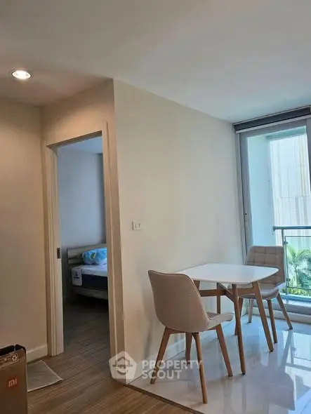 Modern apartment interior with dining area and bedroom view, featuring sleek furniture and natural light.