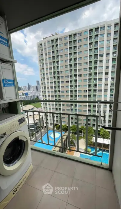 High-rise balcony with washing machine and city view, overlooking pool area.
