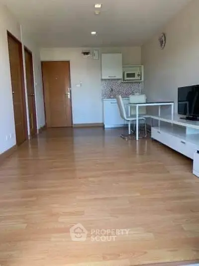 Spacious open-plan living room with modern kitchen and wooden flooring.