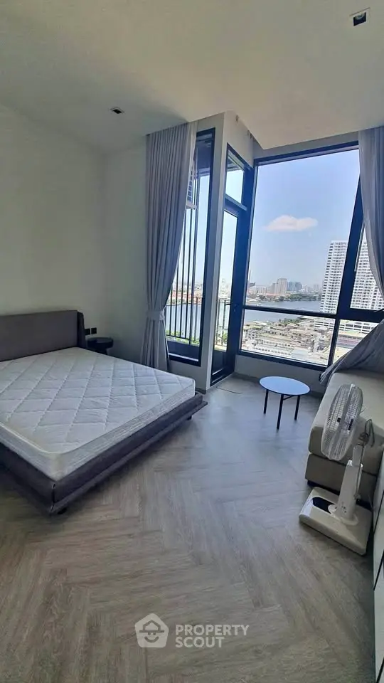 Spacious bedroom with large windows offering stunning city views, modern furnishings, and elegant decor.