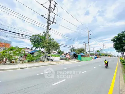 Spacious road view with clear skies and surrounding greenery, ideal for urban development.
