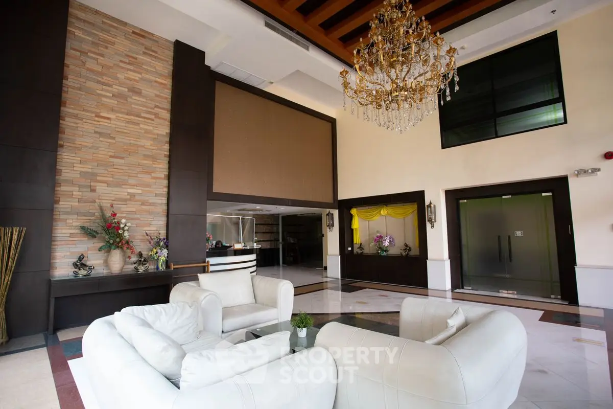Luxurious lobby with elegant chandelier and plush white seating, perfect for welcoming guests.