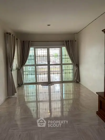 Spacious living room with large windows and elegant curtains