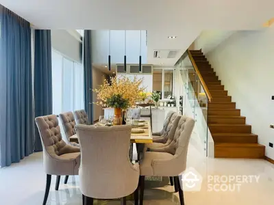 Elegant dining space with plush chairs, modern staircase, and chic decor, perfect for sophisticated urban living.