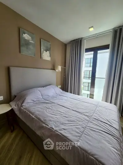 Modern bedroom with stylish decor and large window offering natural light and city view.