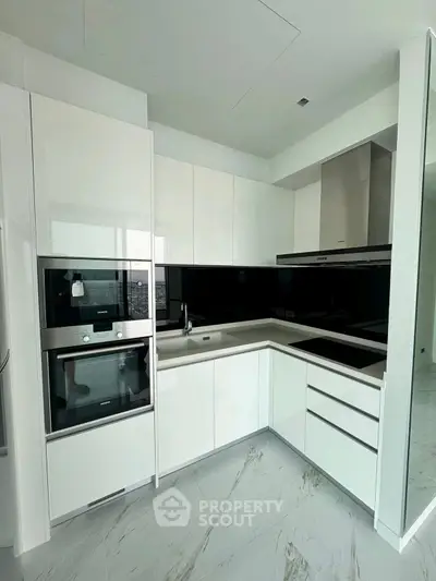 Modern kitchen with sleek white cabinetry and built-in appliances in a contemporary apartment.