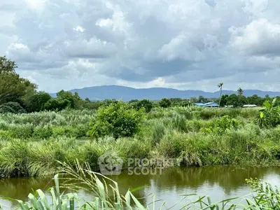 Scenic view of lush green landscape with distant mountains and cloudy sky.