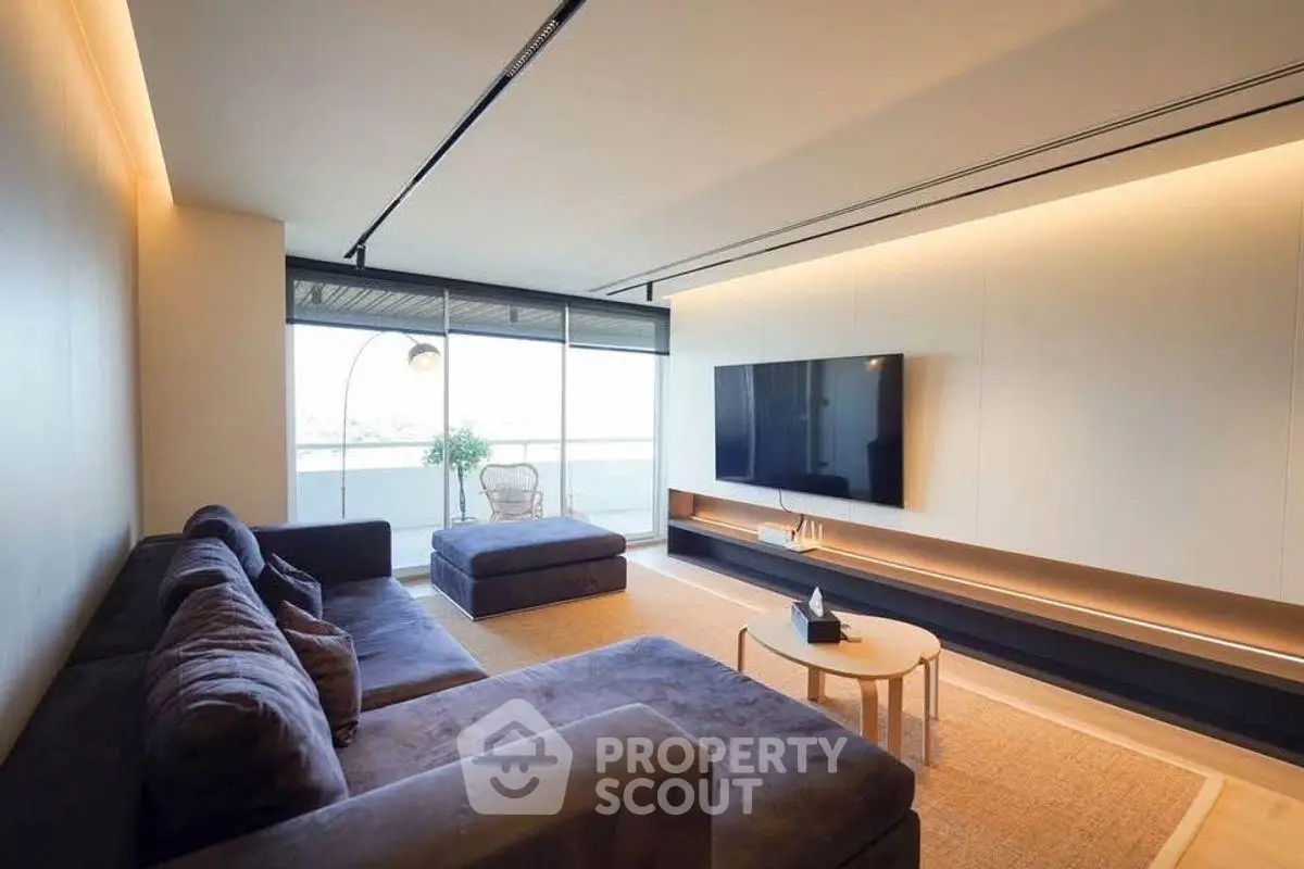 Spacious modern living room with large sofa and wall-mounted TV, featuring sleek design and natural light.