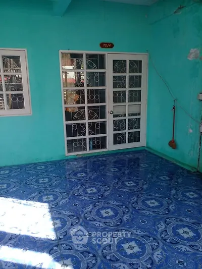 Charming turquoise exterior with decorative blue tiled flooring and white framed windows.