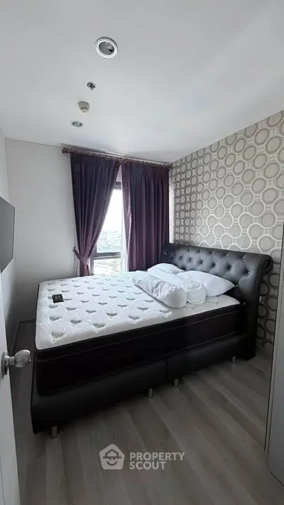Modern bedroom with stylish decor and large window offering city views.