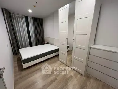 Modern bedroom with minimalist design, featuring a bed, wardrobe, and wooden flooring.