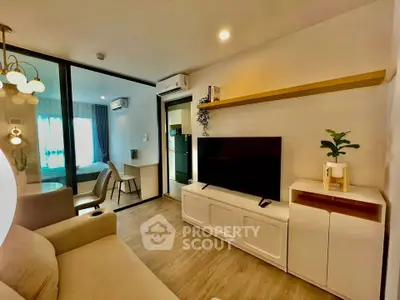 Modern living room with stylish decor and open view to bedroom, featuring sleek furniture and ambient lighting.