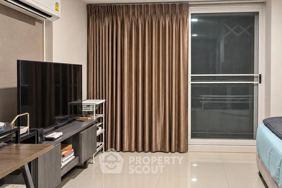 Modern living room with sleek TV setup and sliding glass door to balcony.