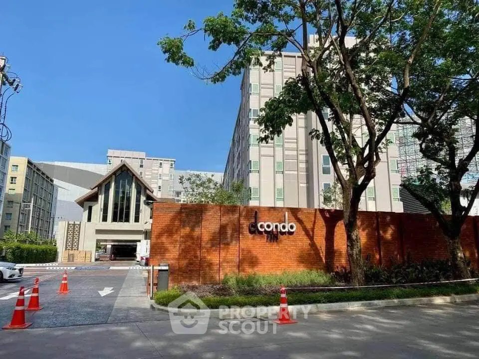 Modern condo entrance with lush greenery and clear blue sky