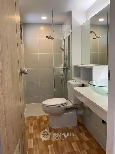 Modern bathroom with glass shower and stylish sink in a sleek apartment.