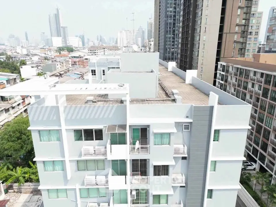 Modern urban apartment building with city skyline view, showcasing contemporary architecture and rooftop access.