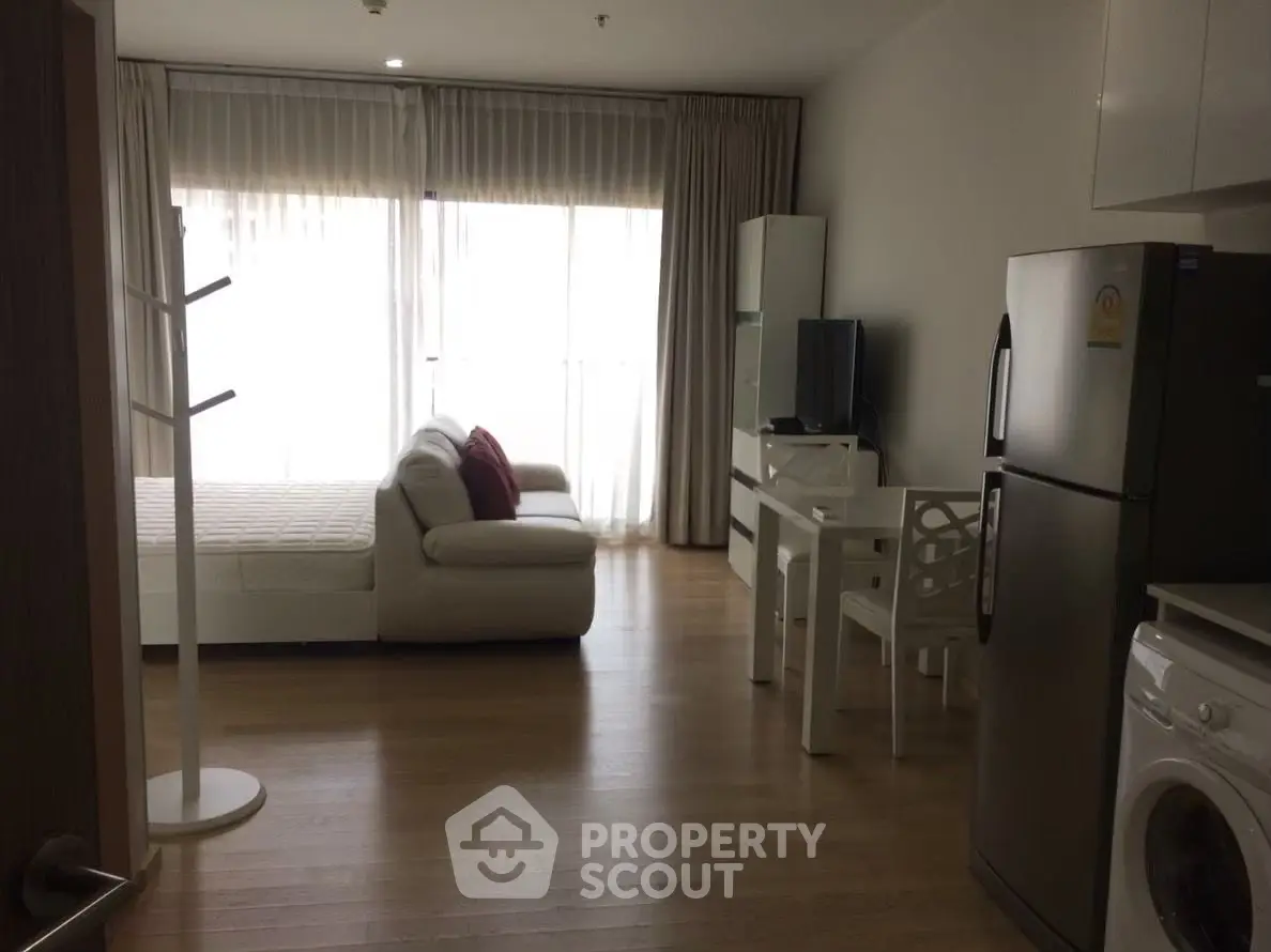 Modern studio apartment with natural light, featuring a cozy living area and compact kitchen.