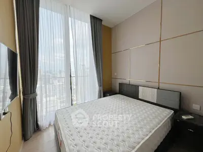 Modern bedroom with large windows and city view, featuring stylish decor and ample natural light.