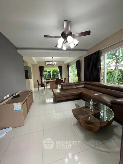 Spacious modern living room with elegant furniture and large windows offering lush garden views.