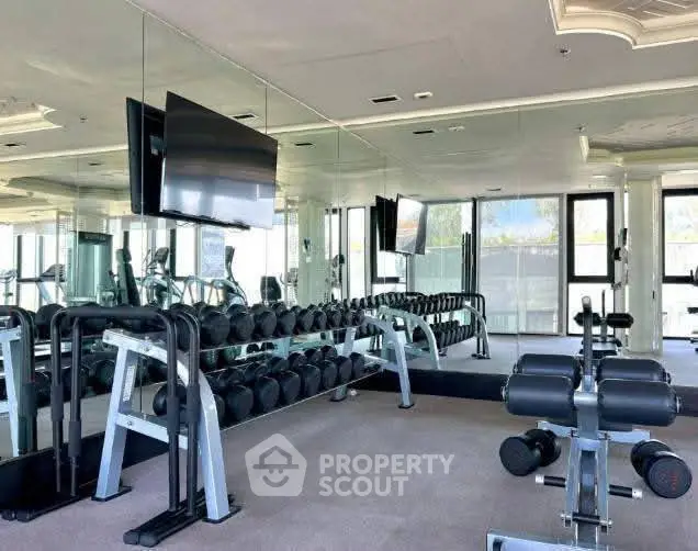 Spacious modern gym with mirrored walls and state-of-the-art equipment in luxury building.