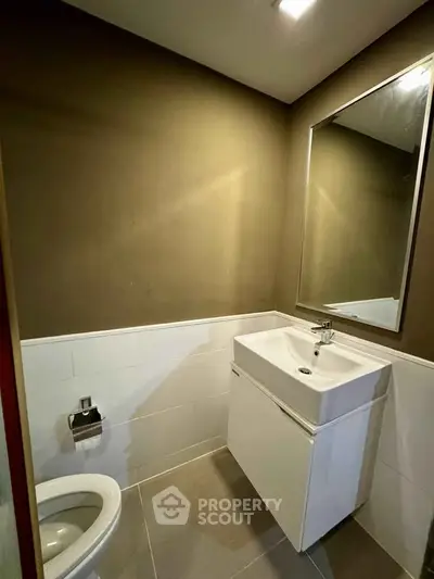 Modern bathroom with sleek sink and mirror, featuring minimalist design and neutral tones.