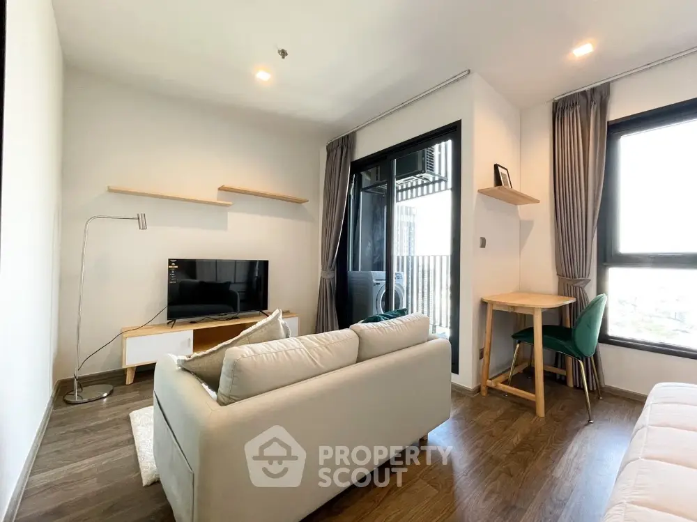Modern living room with cozy sofa, TV, and balcony view in stylish apartment.