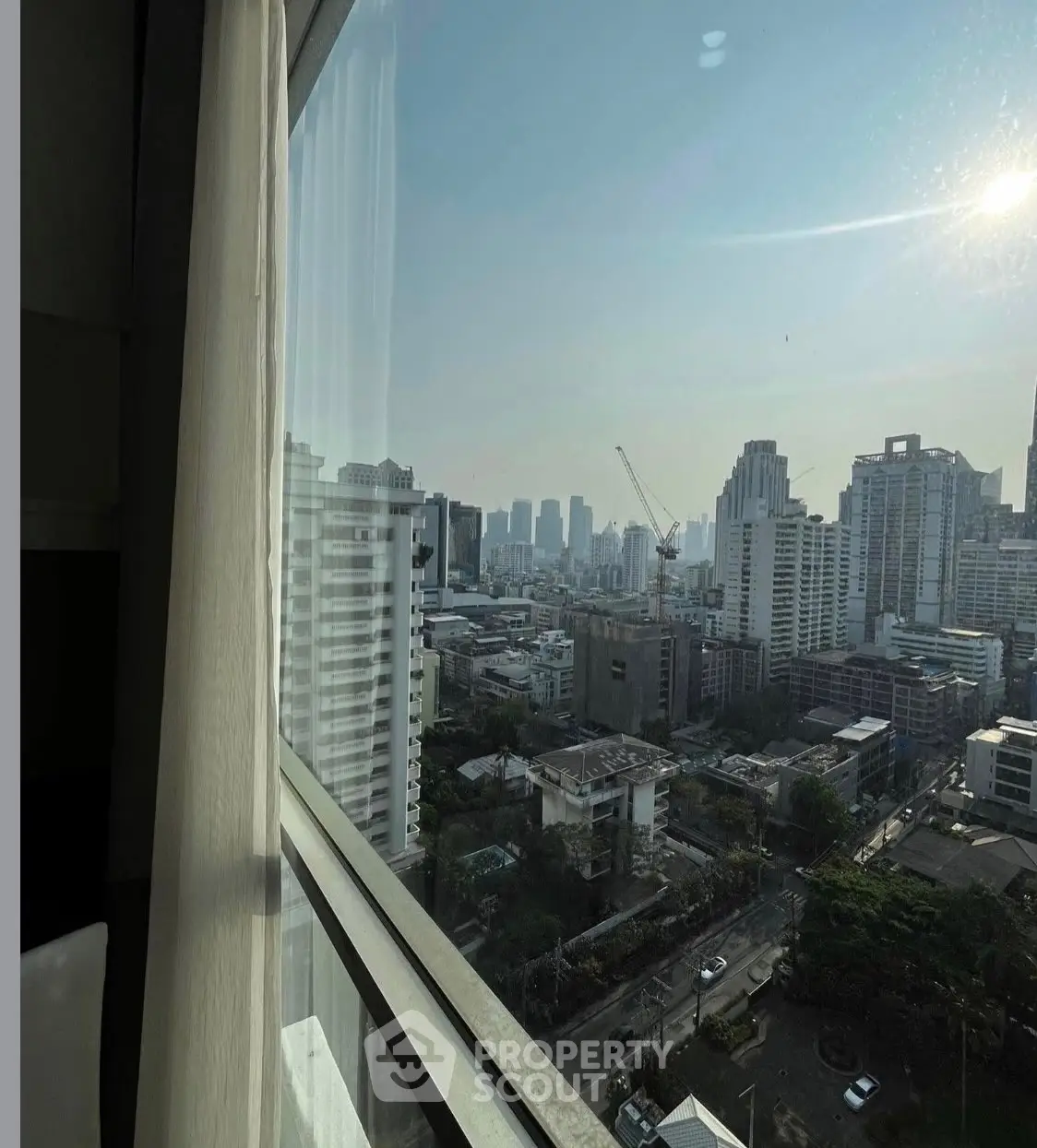 Stunning cityscape view from high-rise apartment window with skyline and construction crane.