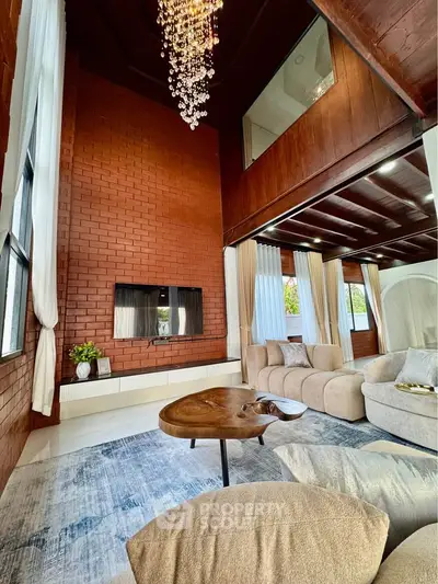 Luxurious living room with high ceilings, elegant chandelier, and cozy seating area.