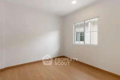 Spacious empty room with wooden flooring and large window, perfect for customization.