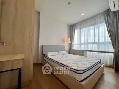 Modern bedroom with large window and natural light, featuring a comfortable bed and stylish wooden furniture.