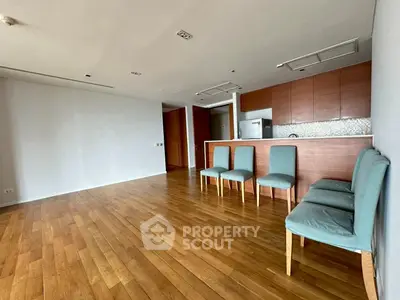 Spacious living room with wooden flooring and modern kitchen in open layout.