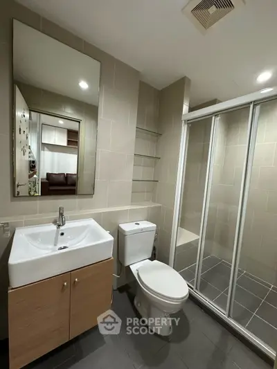 Modern bathroom with glass shower and sleek vanity in contemporary apartment.