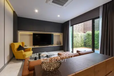 Modern living room with stylish furniture and garden view, featuring a large TV and cozy seating area.