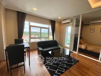 Modern living room with sleek black furniture and large windows offering a scenic view.