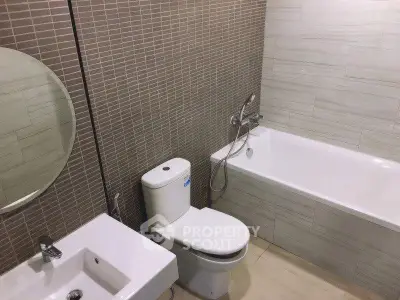 Modern bathroom with bathtub, toilet, and sink featuring stylish tile design.