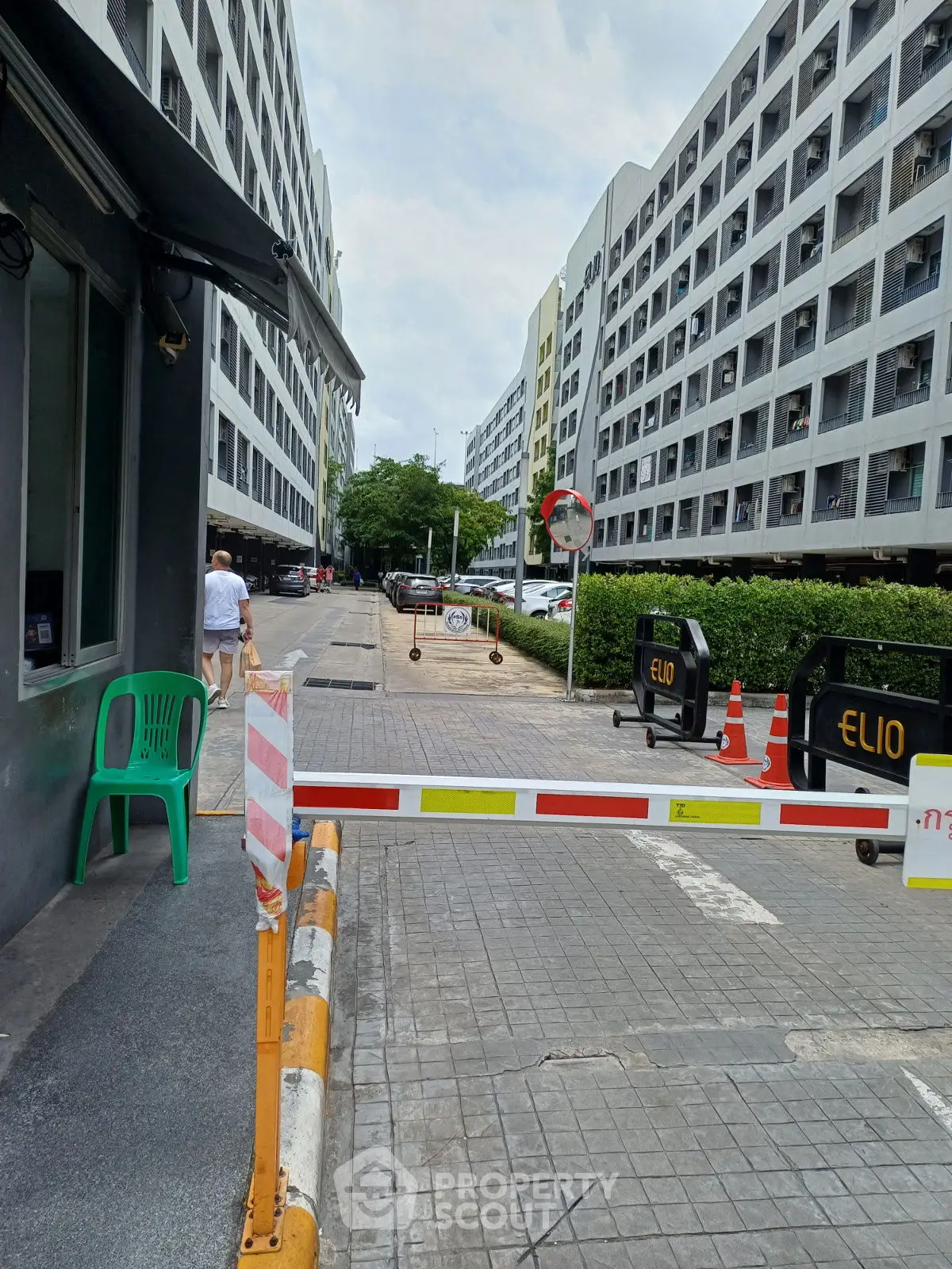 Modern apartment complex entrance with security barrier and lush greenery