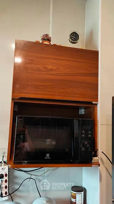 Modern kitchen with built-in microwave and sleek wooden cabinetry.