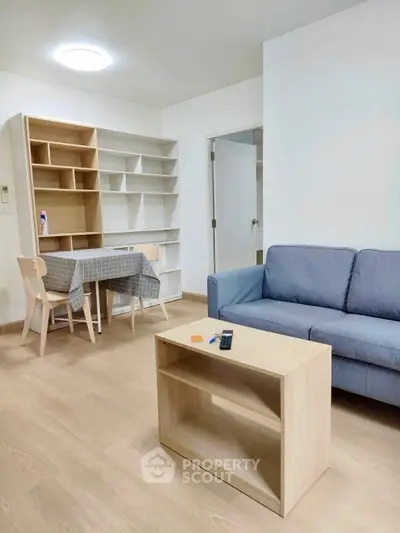 Modern living room with cozy sofa, stylish bookshelf, and dining area in open layout apartment.