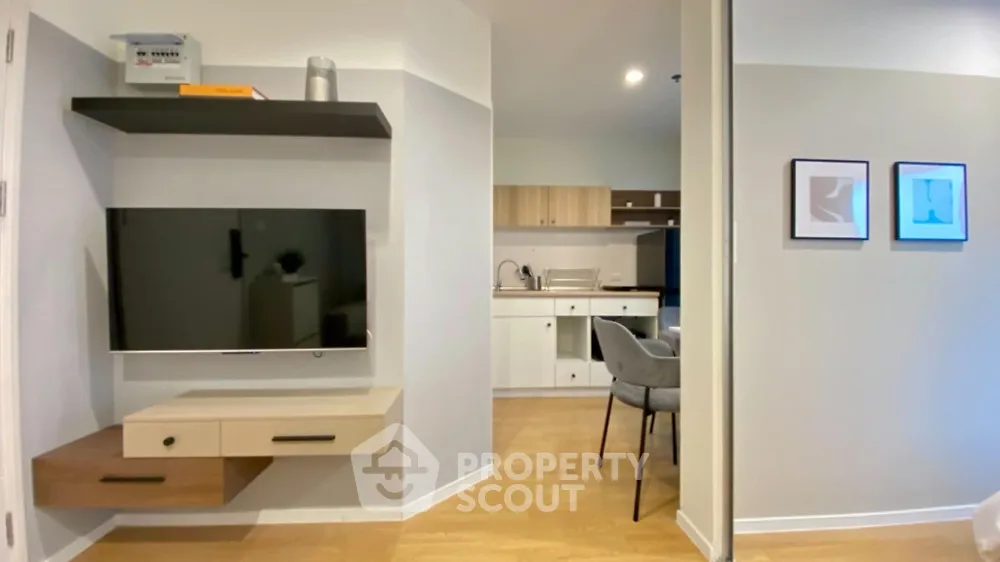 Modern open-plan living room with sleek TV setup and stylish kitchen area