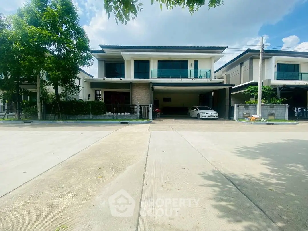 Modern two-story house with spacious driveway and lush greenery in a serene neighborhood.