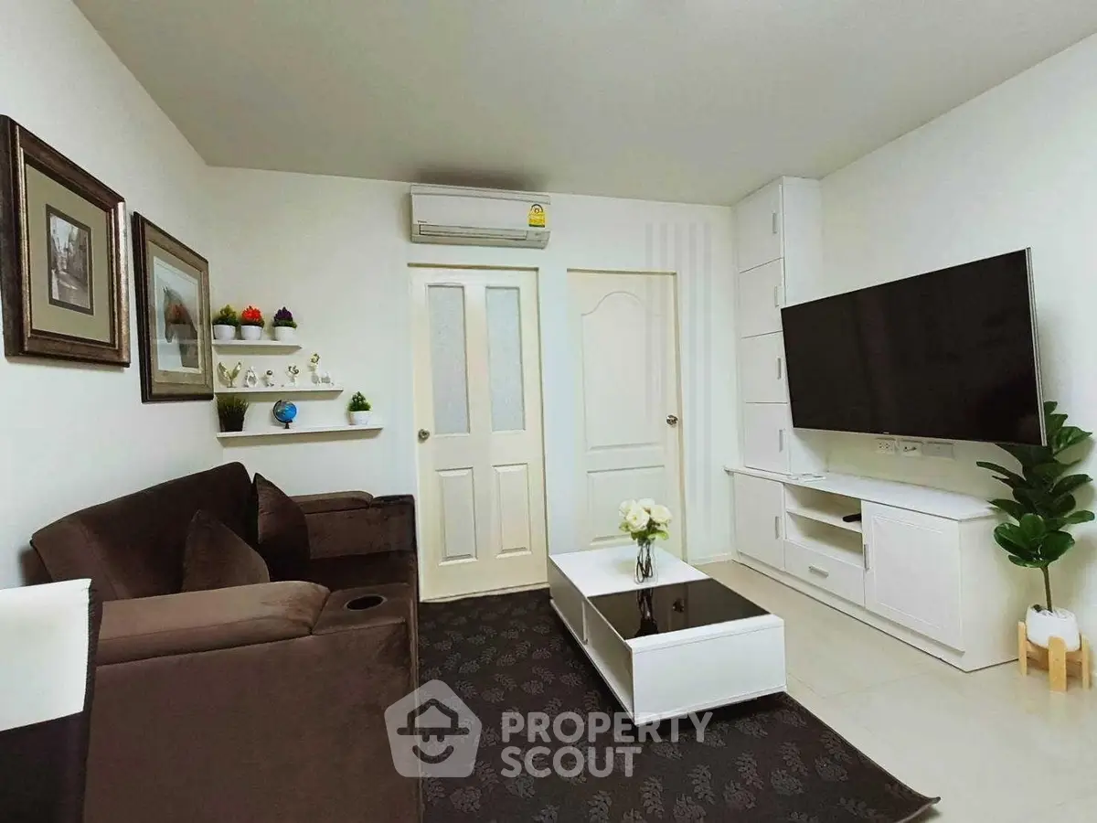 Modern living room with sleek furniture, wall-mounted TV, and elegant decor in a cozy apartment.