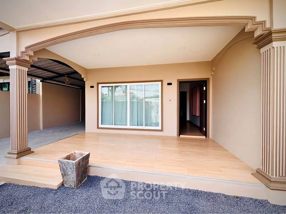 Charming home entrance with elegant columns and spacious patio area.