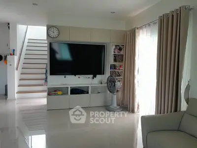 Spacious living room with modern TV setup and natural light