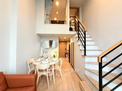 Modern duplex apartment with stylish dining area and staircase, featuring elegant decor and ample natural light.