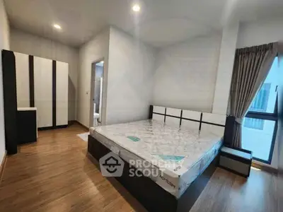 Spacious bedroom with modern furnishings and large window for natural light.