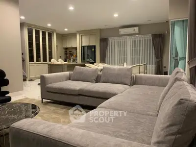 Spacious modern living room with large gray sectional sofa and open kitchen layout.
