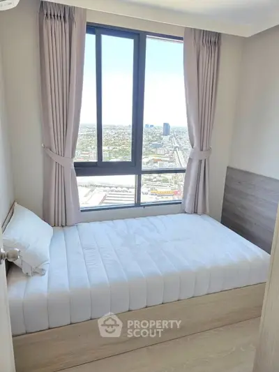 Bright bedroom with large window offering stunning city views, featuring a comfortable bed and elegant curtains.